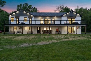 A two-story house with a covered front porch, a dining area with outdoor seating, and a visible address.