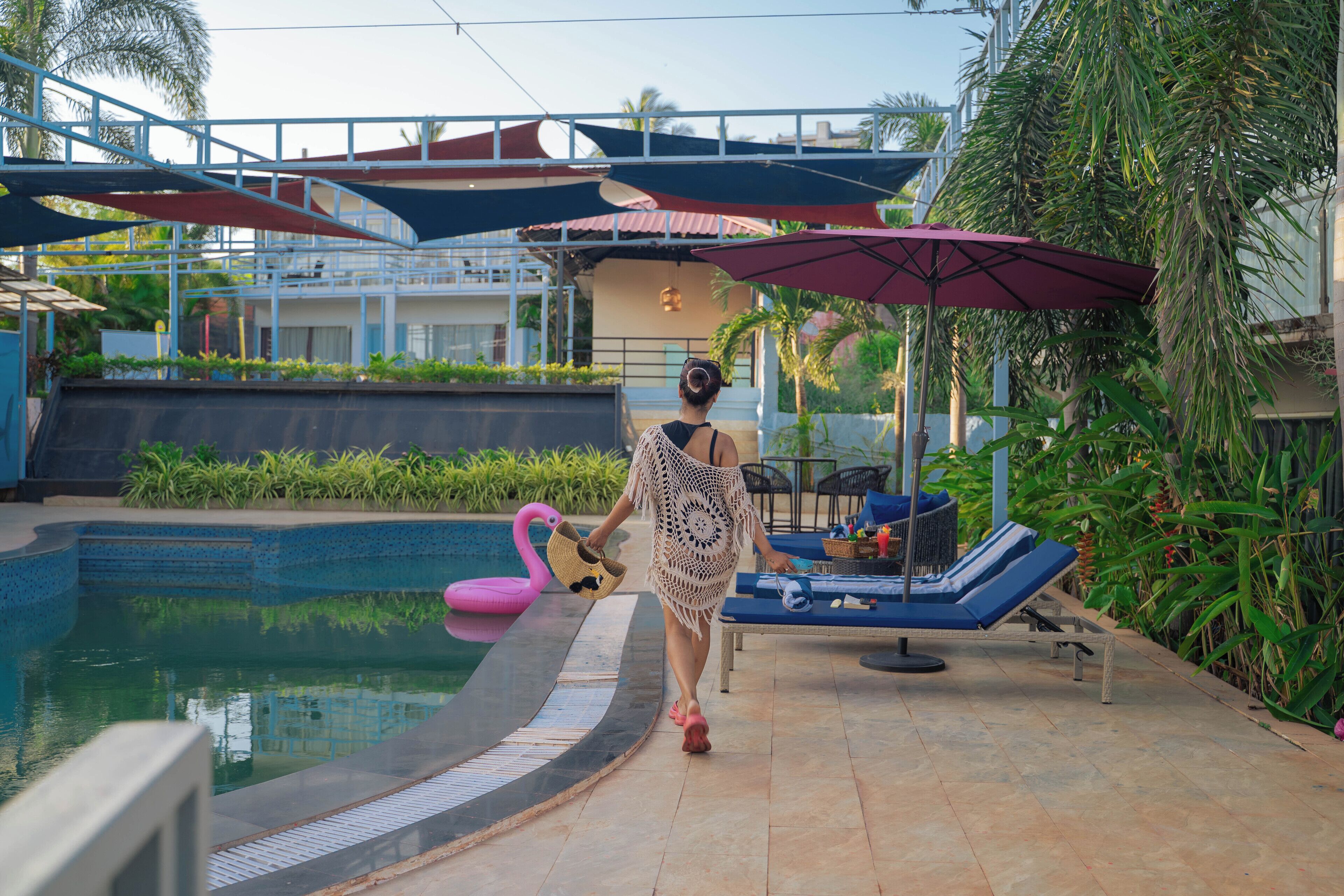A poolside area with lounge chairs, umbrellas, and a flamingo float.