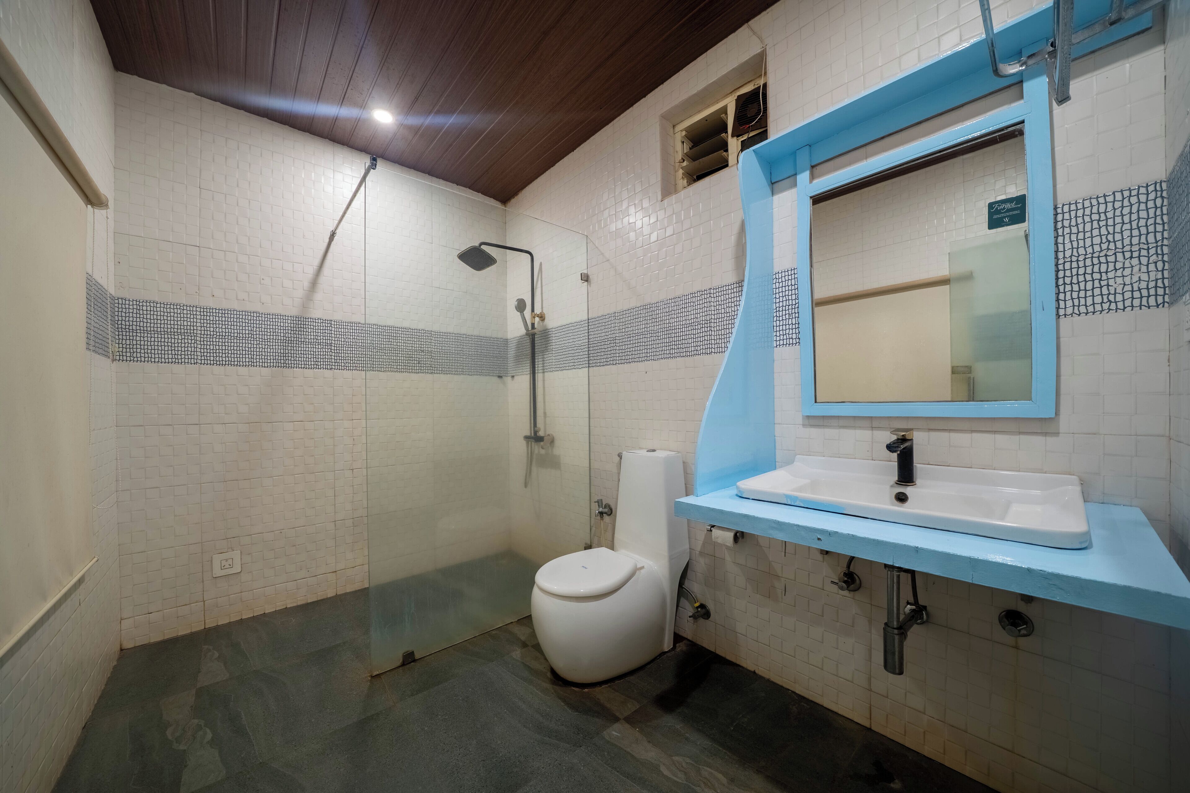 Un baño con inodoro blanco, ducha y lavabo con encimera azul.