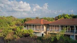 A two-story building with a balcony, surrounded by dense vegetation and trees. - Perfectstayz Koko Maya (Morjim)