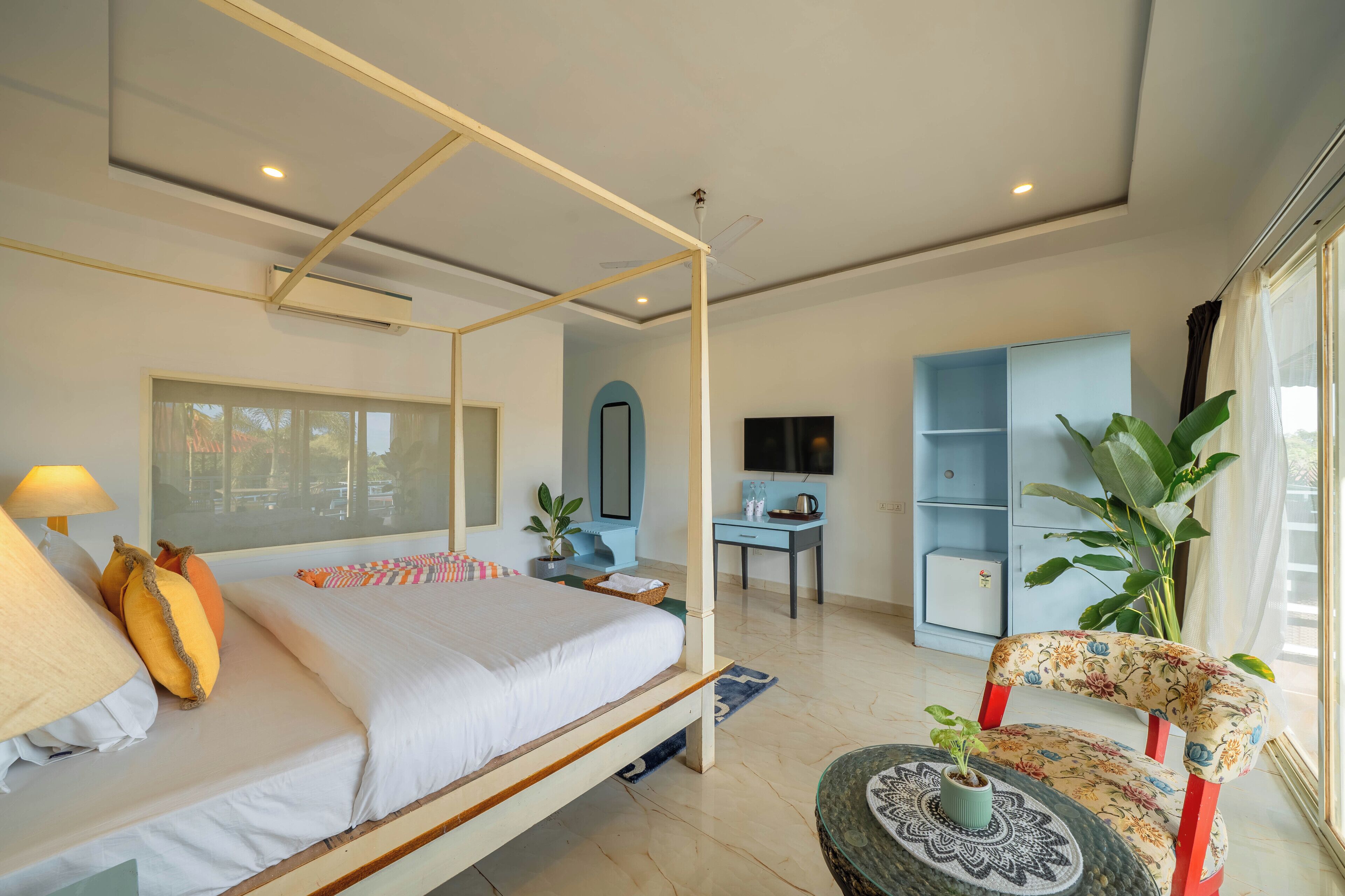 Un dormitorio moderno con cama con dosel, un escritorio, una silla y un ventanal grande.