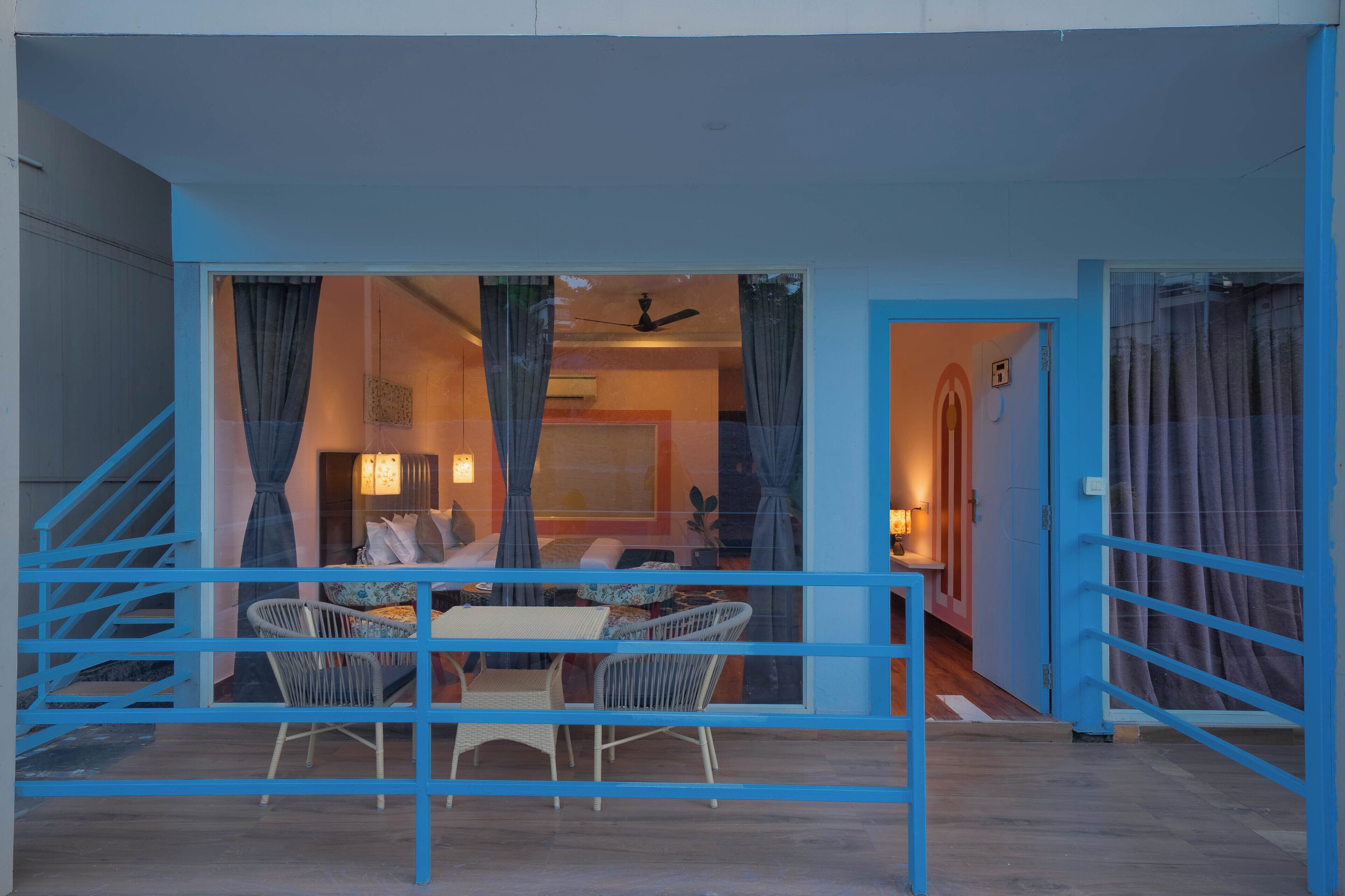 A room with a dining area, a staircase, and a door leading to another room.
