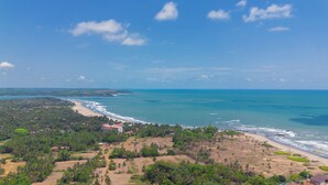 A coastal landscape with a beach, dense vegetation, and a clear sky. - Perfectstayz Koko Maya (Morjim)