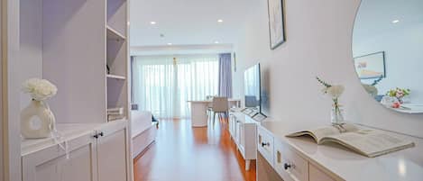 Una habitación de hotel moderna con vestidor, tocador con espejo y zona de escritorio.