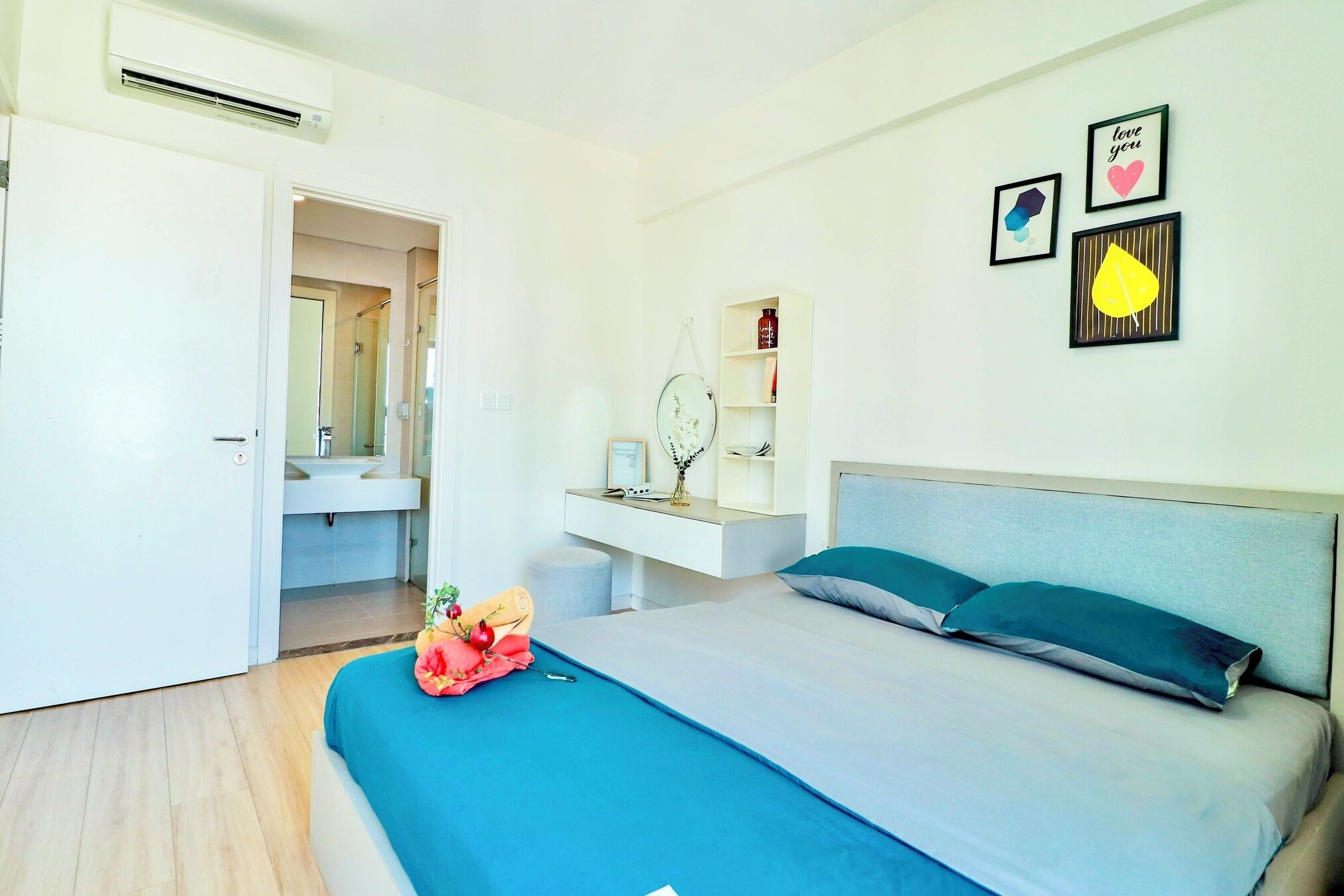 A modern bedroom with a bed, bedside table, and a wall-mounted shelf with decorative items.