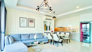 Una sala moderna con un sofá azul, una mesa de centro de vidrio y un comedor con sillas blancas.