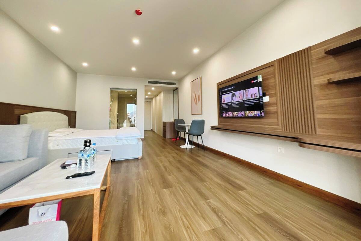 Une chambre d’hôtel moderne équipée d’un lit, d’un bureau, d’un téléviseur fixé au mur et d’un plancher en bois.