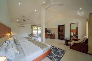 Quarto de hotel com cama grande, mesa de trabalho, televisão e varanda com vista.