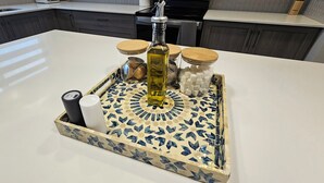 Eine Küchenarbeitsplatte mit einer dekorativen Tablett, das eine Flasche, Gläser und einen zylindrischen Behälter enthält.