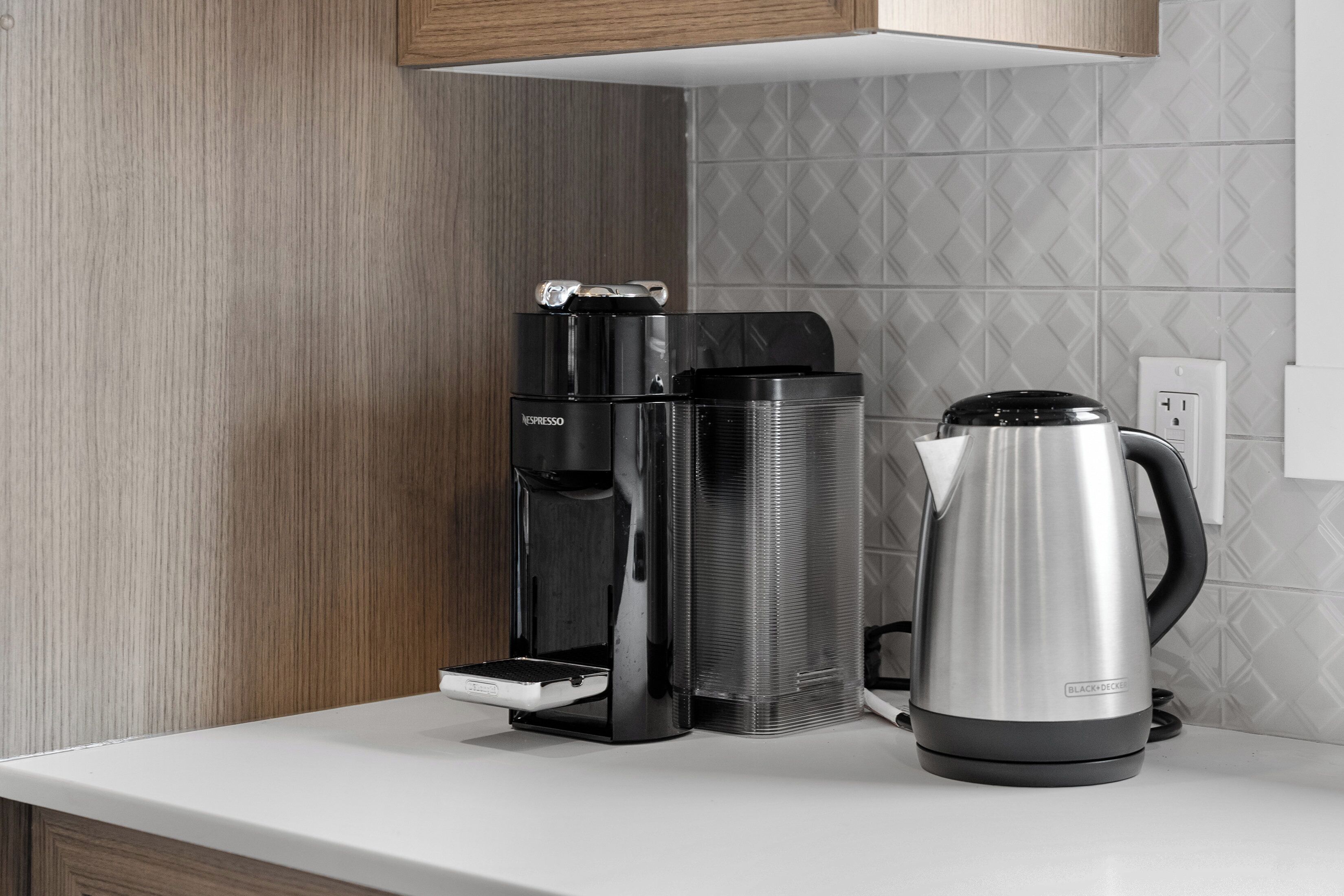 Une cuisine équipée d’une machine à café, d’un distributeur d’eau et d’une bouilloire sur le plan de travail.