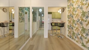 Een moderne keuken met een centraal eiland, hanglampen en een wand met een tropisch bladpatroon.