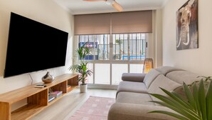 Een woonkamer met een flatscreen televisie, een houten tv-meubel, een bank en een plafondventilator.