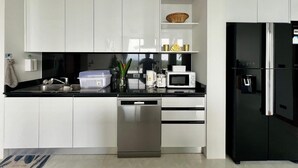 A modern kitchen with white cabinets, a black refrigerator, a dishwasher, a microwave, and a sink. - Michel Tropical Seaview Pool Villas  (Mae Nam)