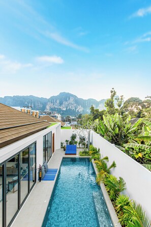 Un edificio moderno con piscina, amplias ventanas y vistas a montañas.