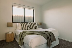 Un dormitorio con cama, dos lámparas de noche, un ventanal y vistas al exterior.