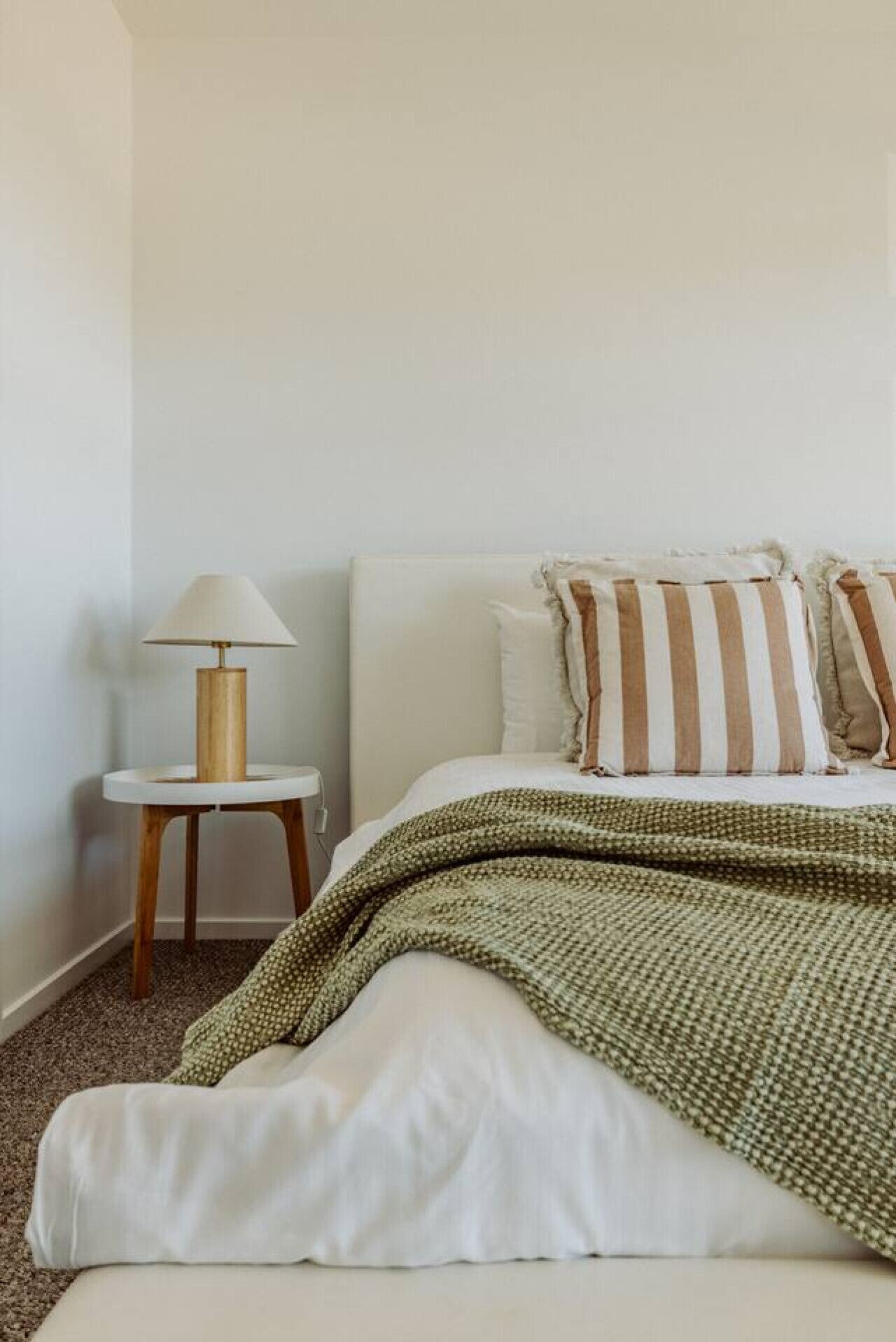 A bedroom with a bed, a bedside lamp, and a striped pillow.