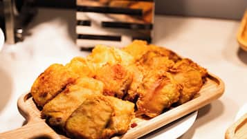 Ein hölzerner Serviertablett mit einer Portion frittiertem Essen, möglicherweise Hähnchen, auf einem weißen Teller.
