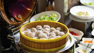 A steamer with dumplings and various dishes in the background.