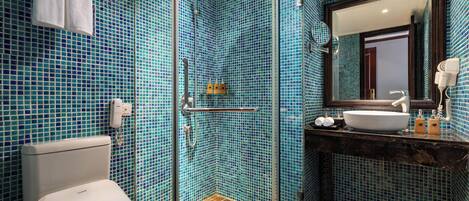A bathroom with a glass-enclosed shower, a white toilet, and a sink with a mirror above it.
