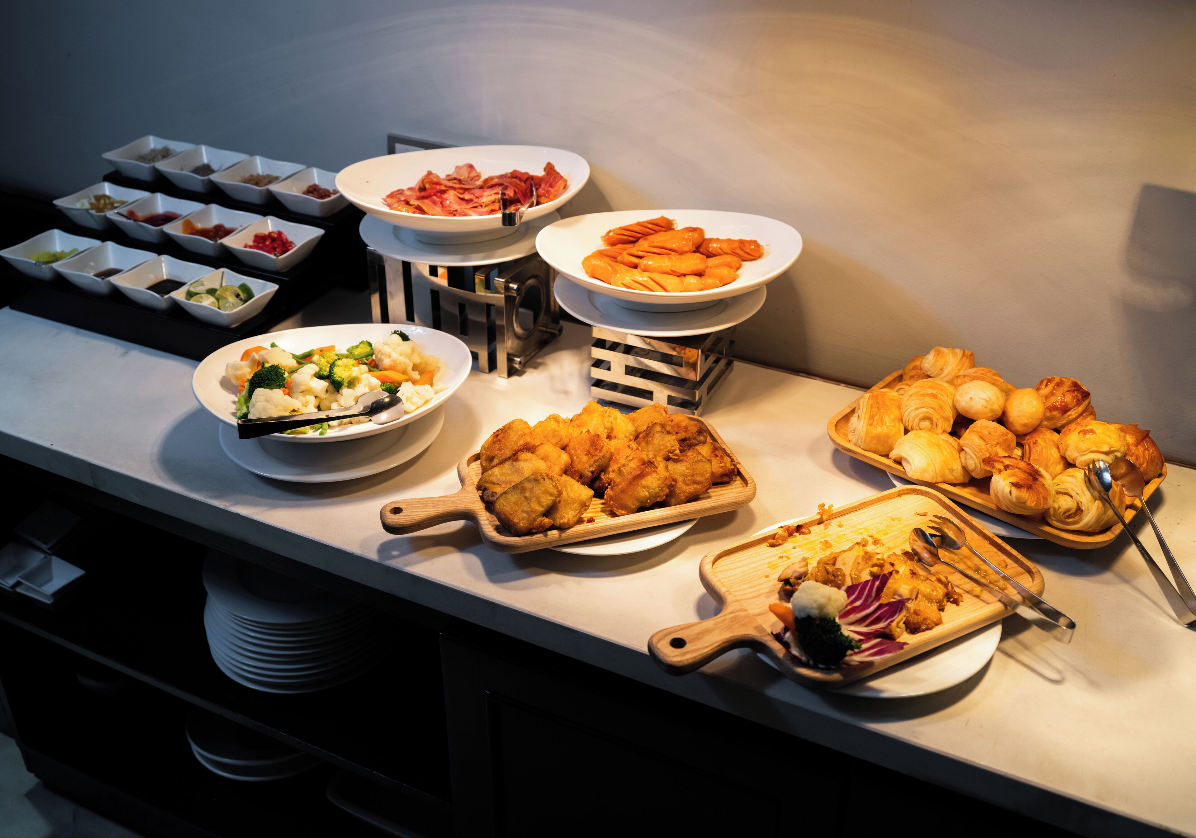 A buffet table with various dishes including seafood, vegetables, and pastries.