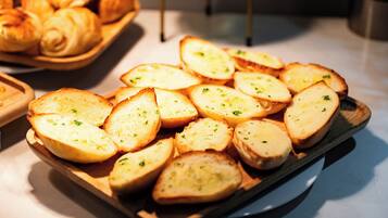 A wooden serving tray with sliced bread garnished with herbs, placed on a countertop.