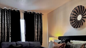 A bedroom with a bed, a sofa, and a wall-mounted lamp. - Modern 3BR Retreat with Comfort & Style Near Disney (Kissimmee)