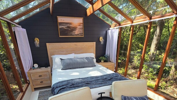Ein gemütliches Schlafzimmer mit Holzbalkendecke, einem Bett, zwei Stühlen und einem kleinen Tisch.