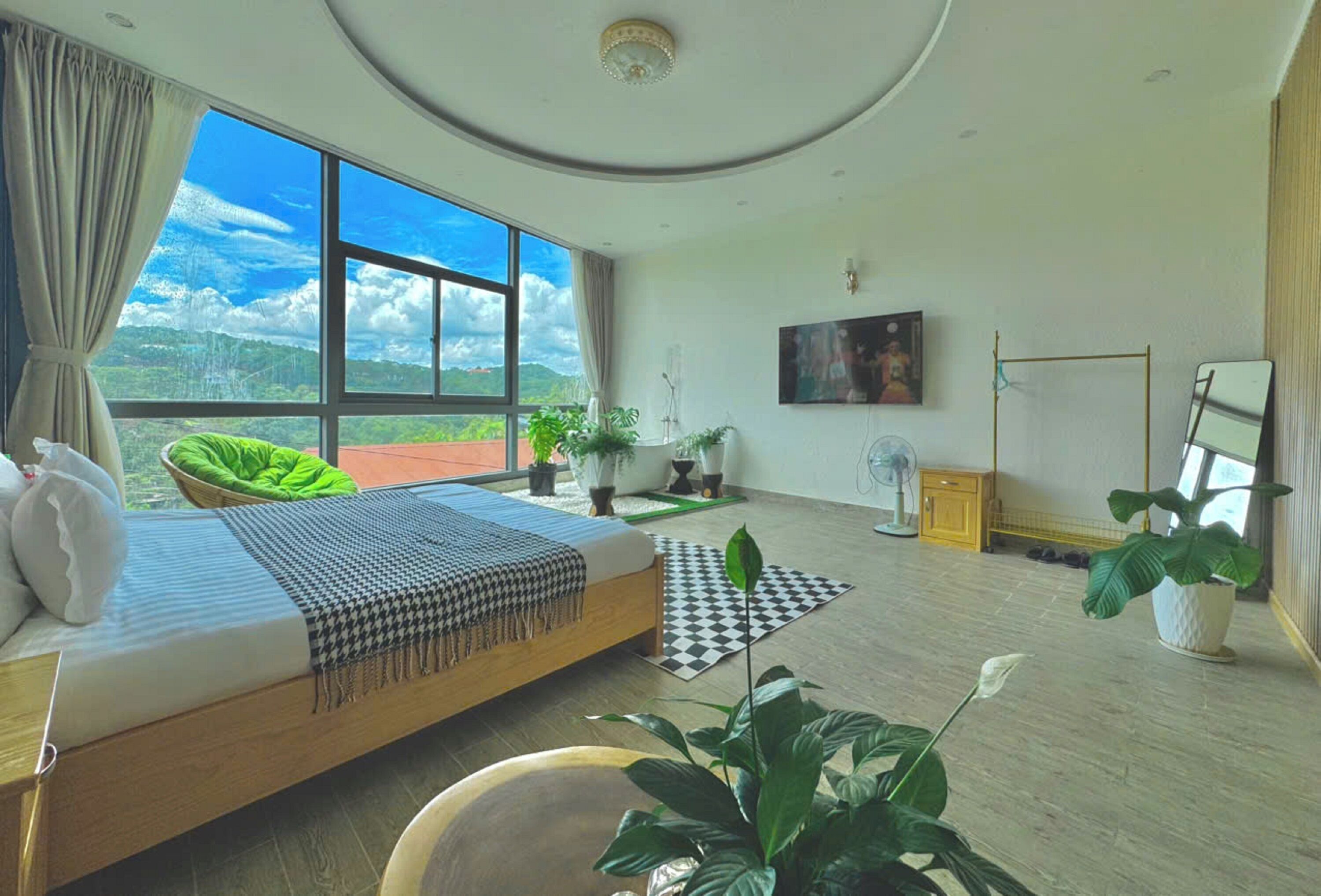 Een moderne slaapkamer met een groot bed, uitzicht op het omliggende landschap, een televisie en een spiegel.