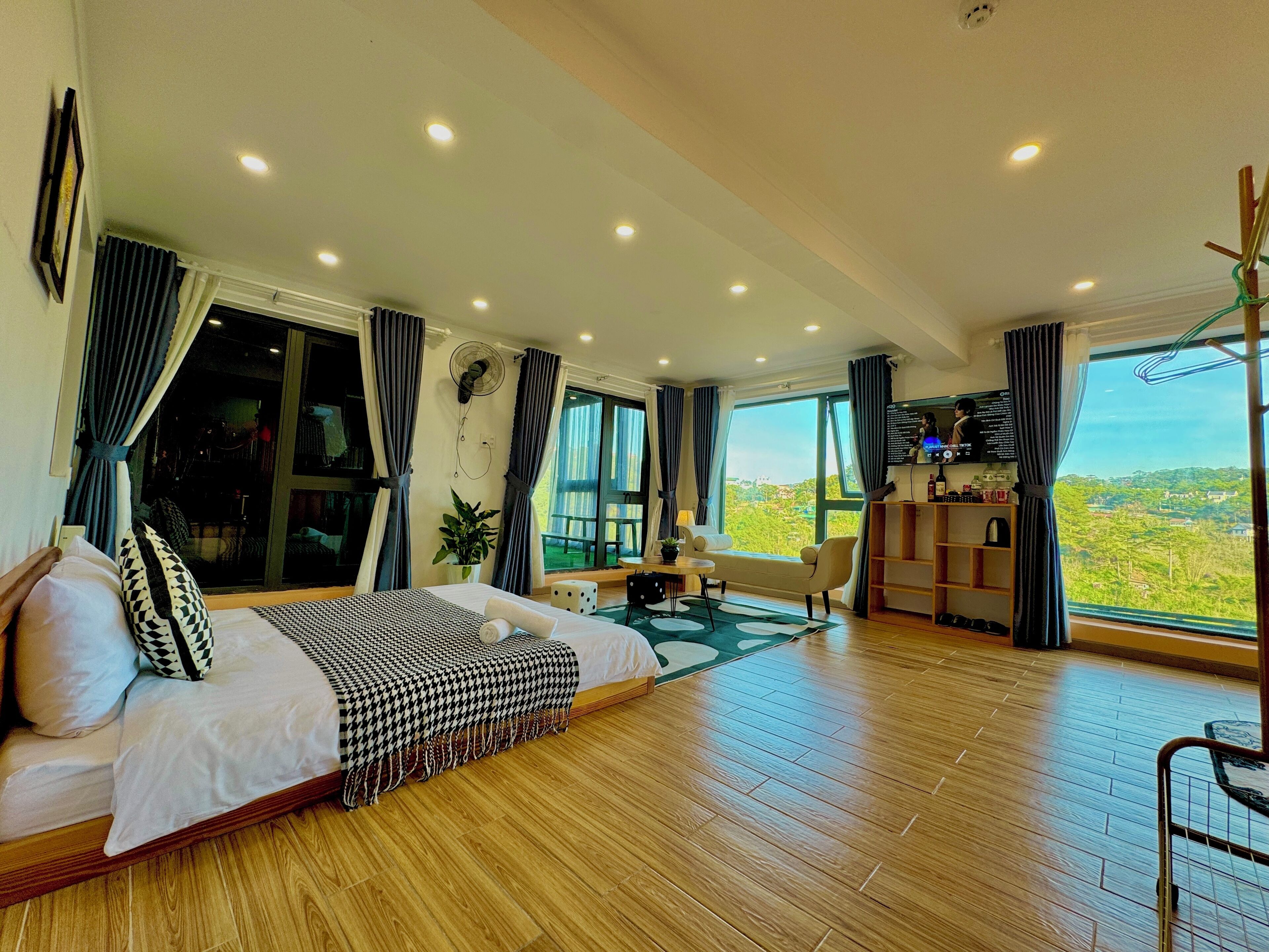 A spacious bedroom with a large bed, a desk, and a view of the landscape.