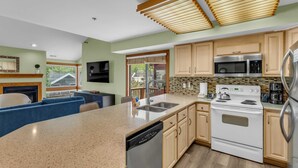A modern kitchen with wooden cabinets, a stainless steel refrigerator, a microwave, and a dishwasher.