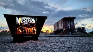 Un letrero con temática del oeste y un edificio rústico al fondo.