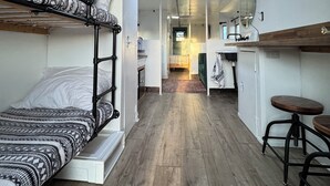Una habitación compacta en un hostal con literas, una kitchenette y un pequeño comedor.
