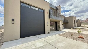 Un bâtiment moderne à deux étages, doté d’un grand portail de garage, d’un balcon et d’une allée aménagée.