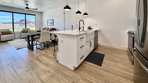 Une cuisine moderne dotée d’un îlot central, de meubles blancs et d’un réfrigérateur en acier inoxydable.