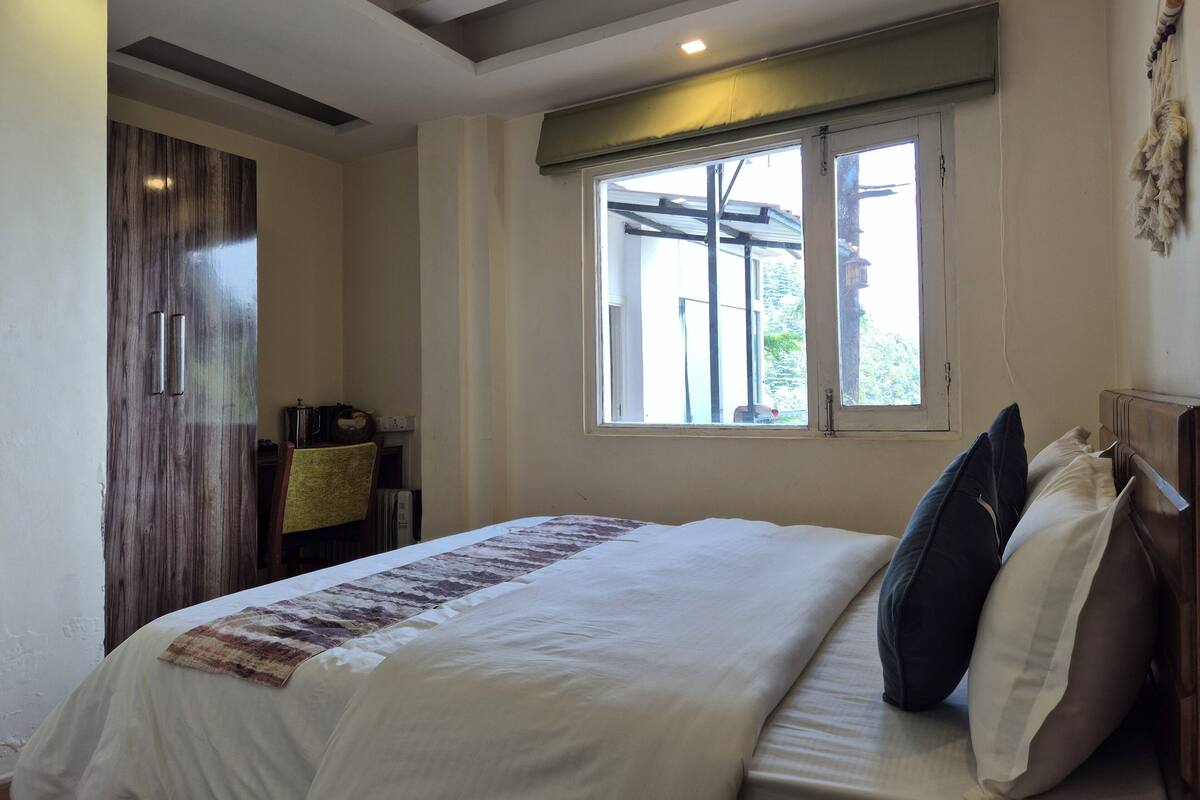 Een slaapkamer met een bed, een raam, een kledingkast en een bureau.