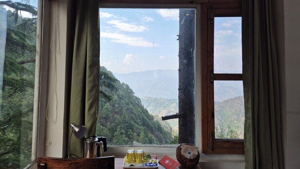 Quarto com uma grande janela que oferece vista para uma paisagem montanhosa.