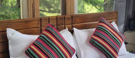 Uma cama com almofadas brancas e uma almofada listrada colorida.
