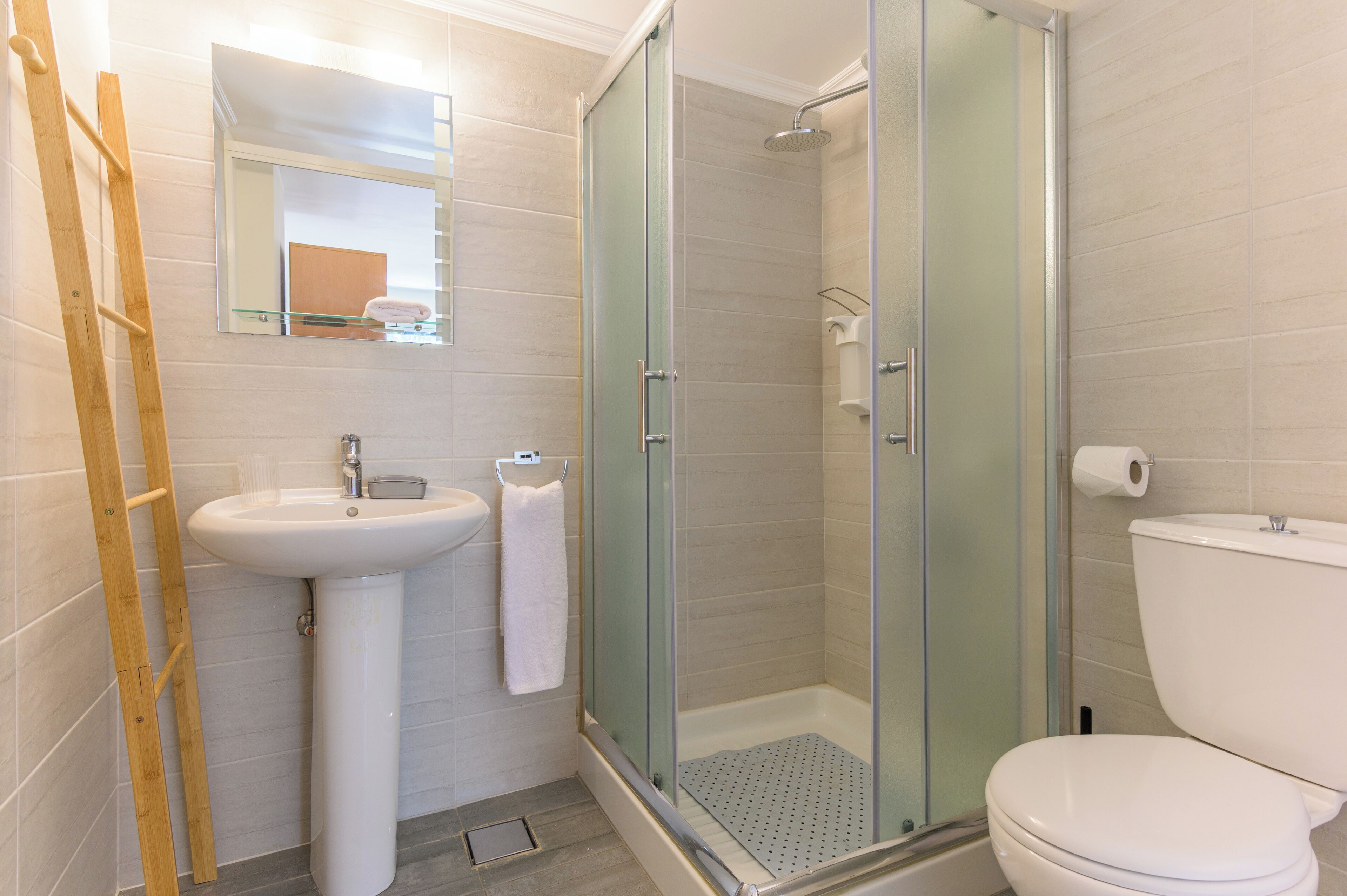 A bathroom with a glass-enclosed shower, a pedestal sink, and a toilet.