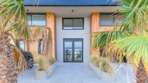 A modern building with a central entrance, flanked by wooden panels and potted plants. - Sea Lofts-Kfar Abida Oceanfront Retreats (Batroun)