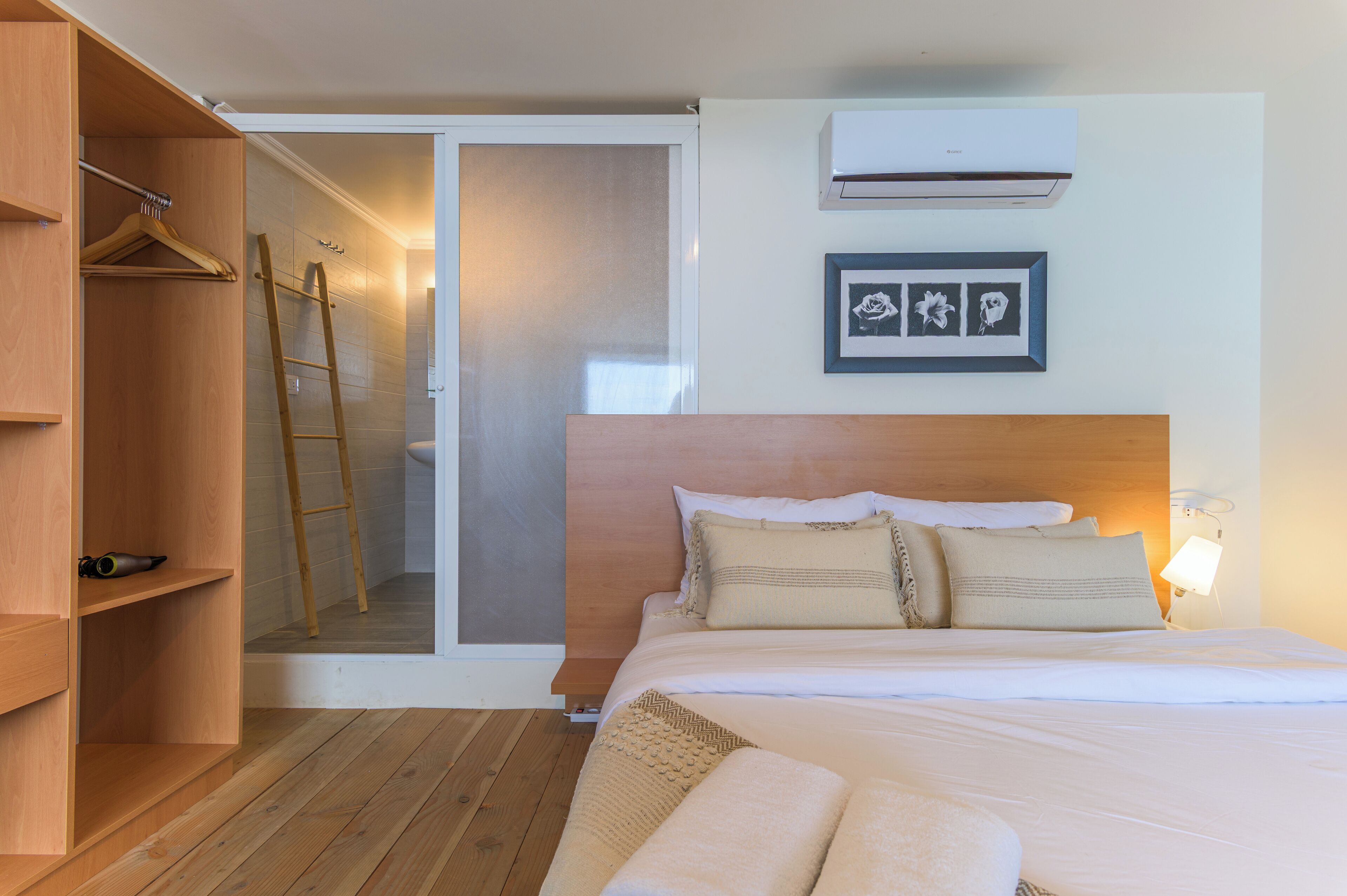 A bedroom with a wooden bed, a wardrobe, a ladder, and a framed picture on the wall.