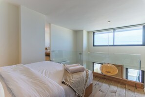 A bedroom with a large bed, a glass balcony, and a view of the sea. - Sea Lofts-Kfar Abida Oceanfront Retreats (Batroun)
