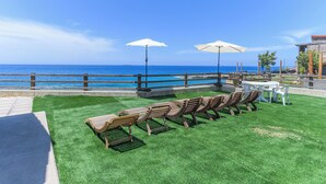 A patio with outdoor seating and umbrellas overlooking a coastal view. - Sea Lofts-Kfar Abida Oceanfront Retreats (Batroun)
