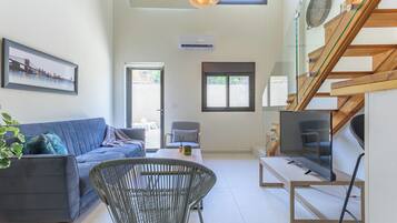 A modern living room with a sofa, a chair, a table, and a staircase.