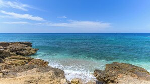 A coastal landscape with clear blue waters, rocky shoreline, and distant ships. - Sea Lofts-Kfar Abida Oceanfront Retreats (Batroun)