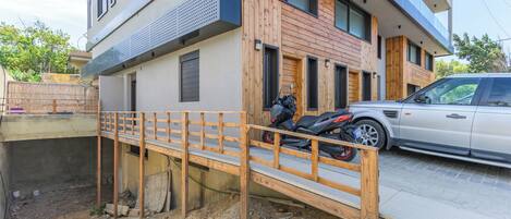 A modern building with a wooden facade, a motorcycle parked in front, and a car parked on the street.