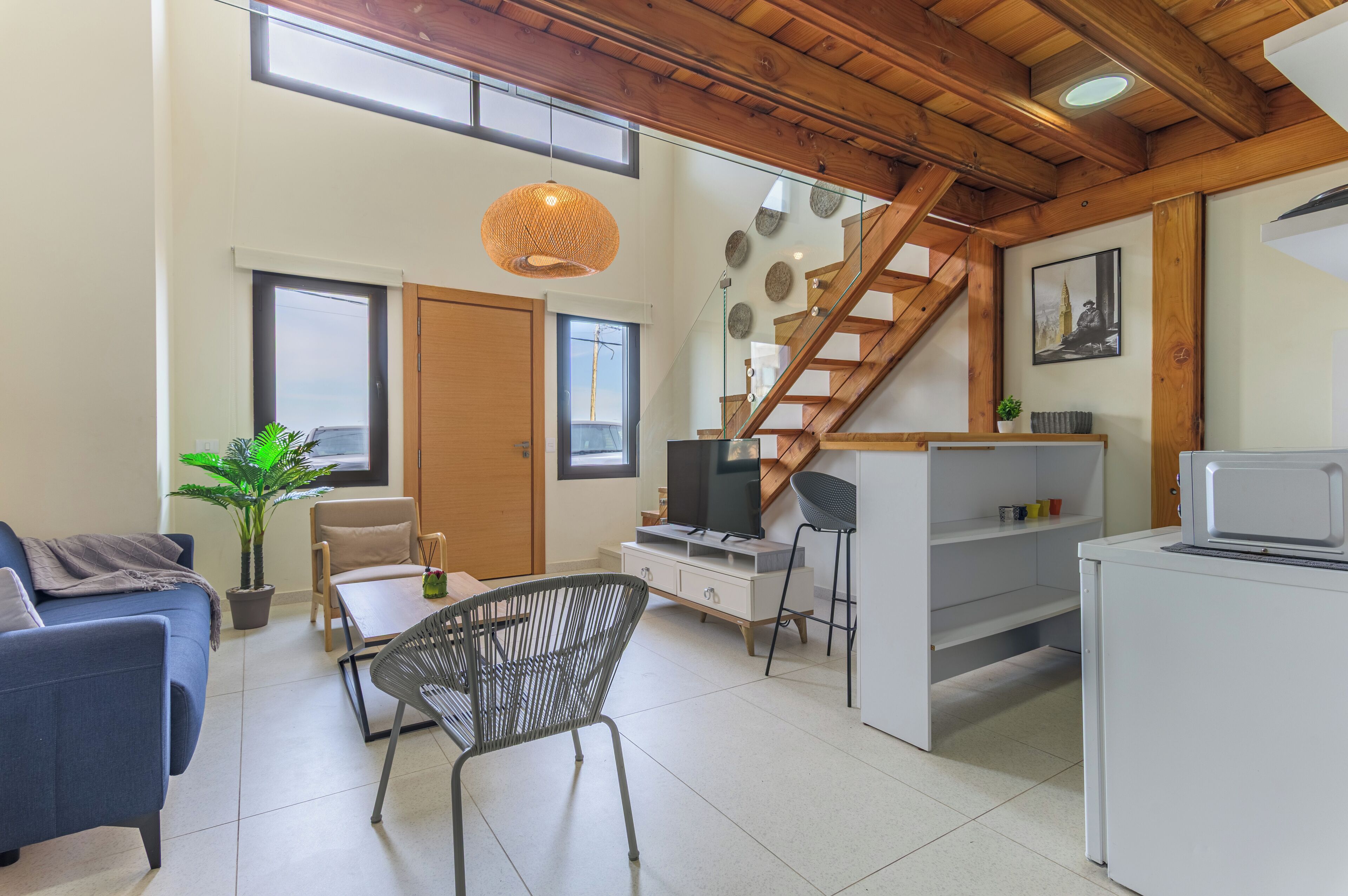 A modern living space with a staircase, a dining area, a TV, and a washing machine.