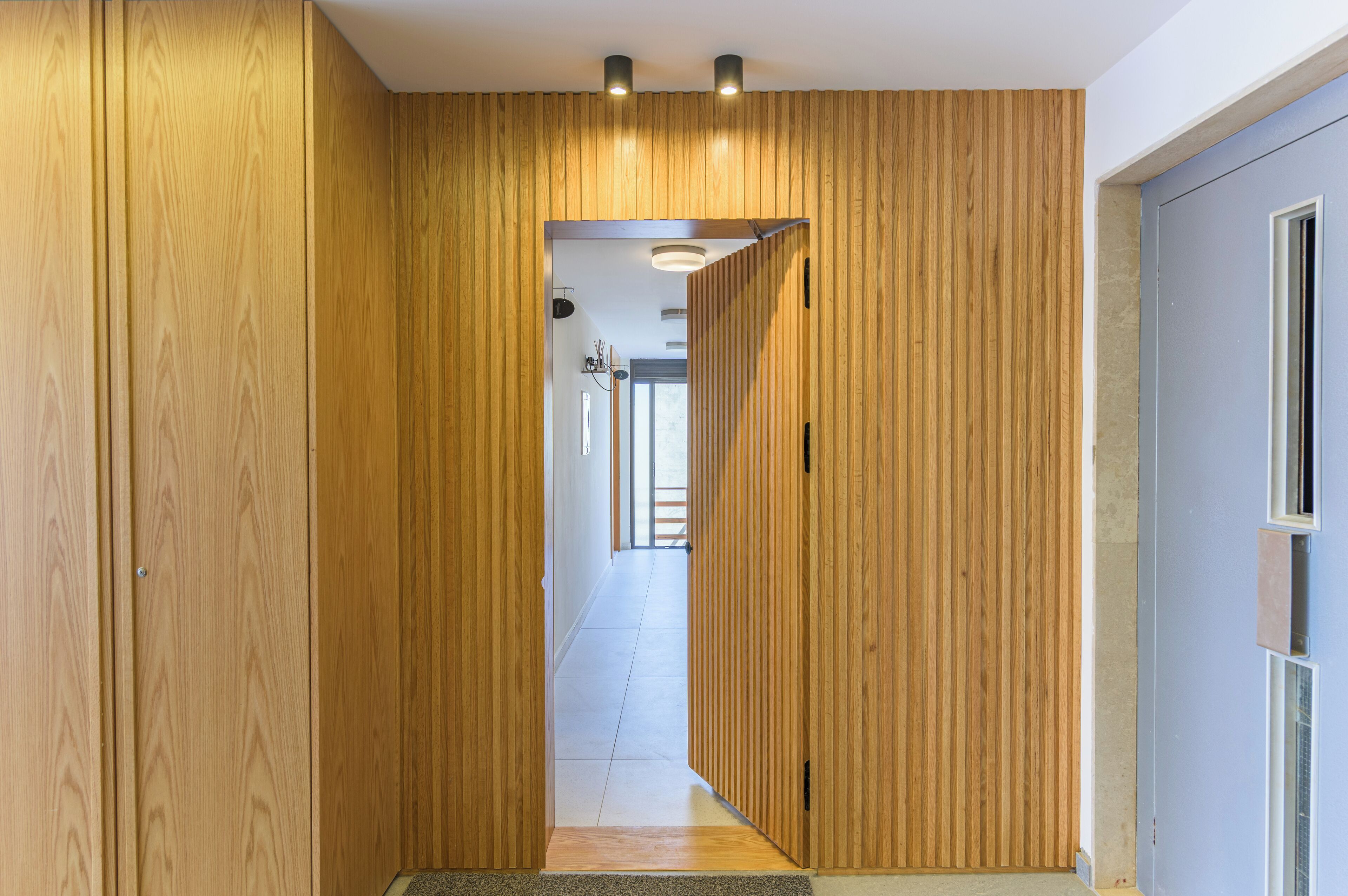 A hallway with wooden paneling and recessed lighting.