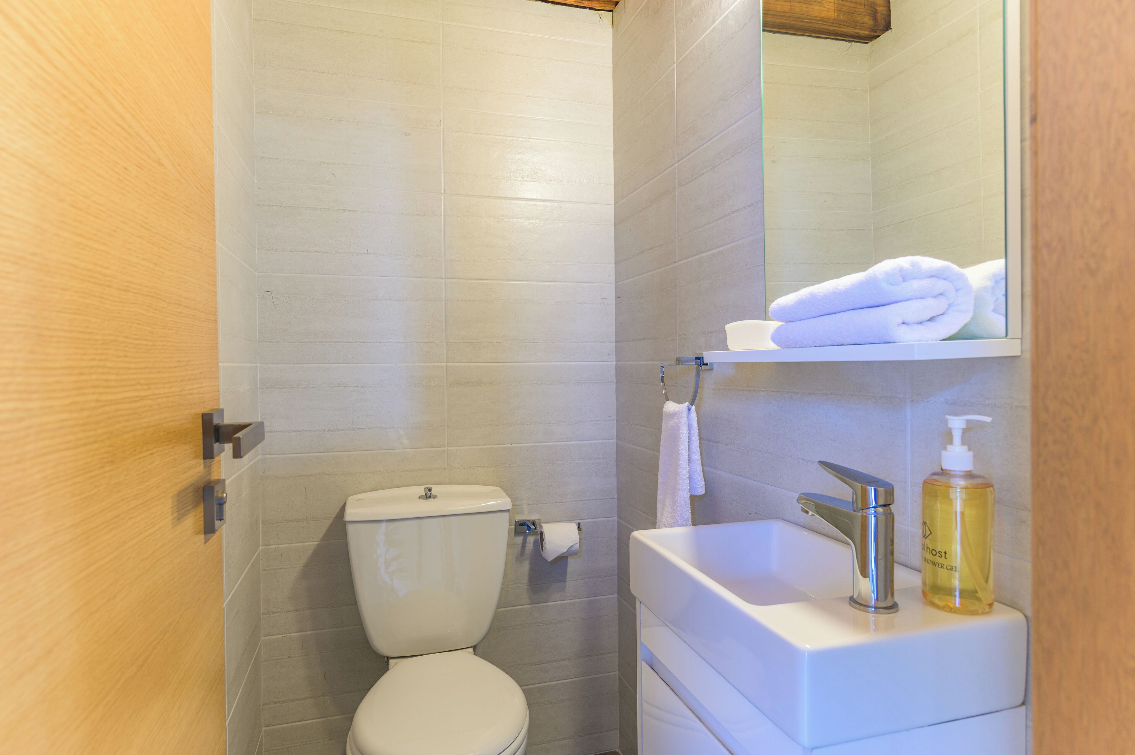 A bathroom with a toilet, a sink with a soap dispenser, and a towel hanging on a rack.