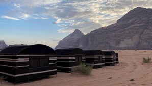 Un paysage désertique avec une rangée de tentes rayées.