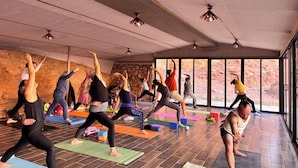 Un cours de yoga dans une pièce dotée de grandes fenêtres et d’un mur en pierre.
